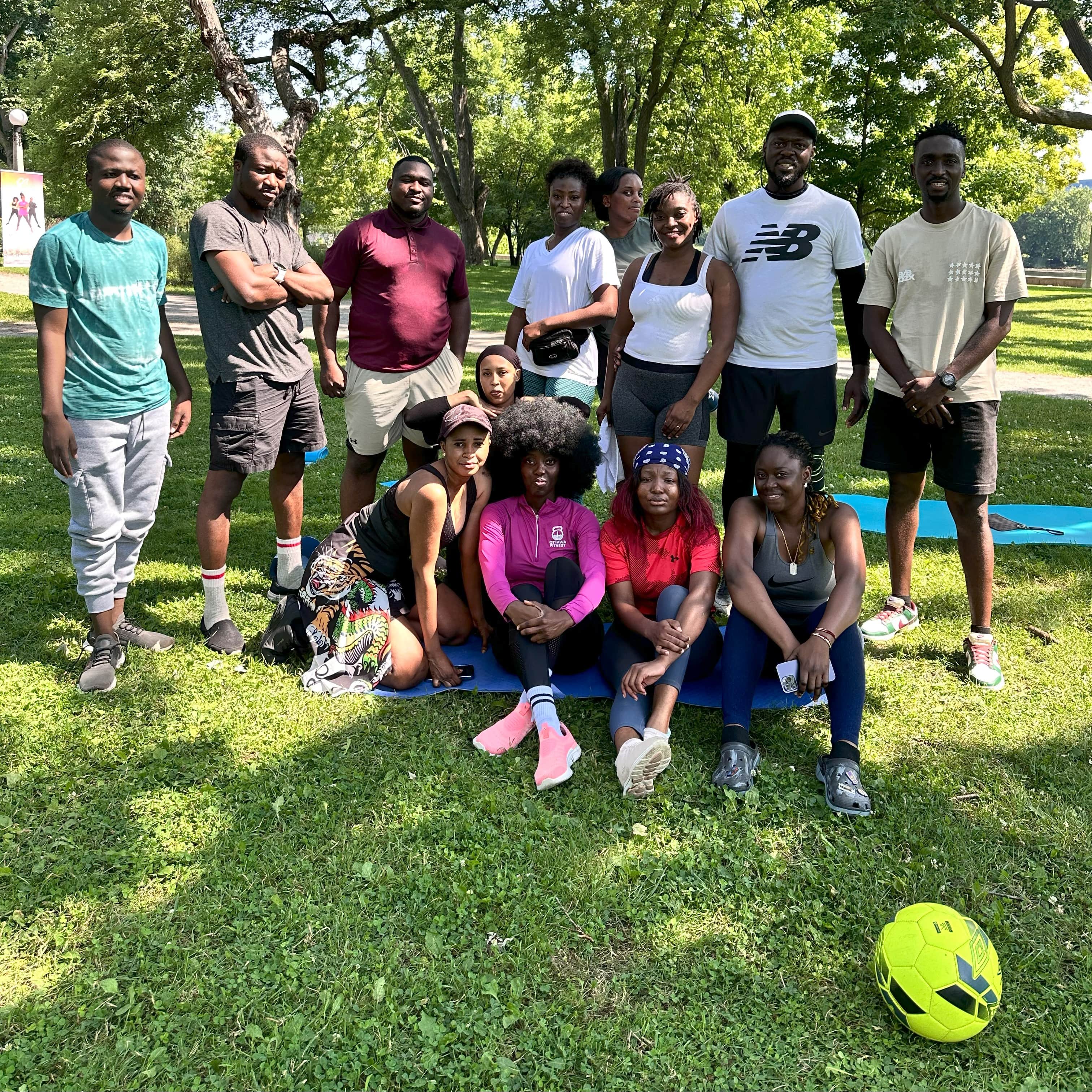 The group sitting together on a mat in the park after a summer session
